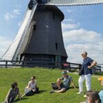 Tour group sitting in frot of a windmill on the Private Amsterdam Windmill Tour