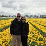 Two people standing in a field of yellow tulips durig a tour